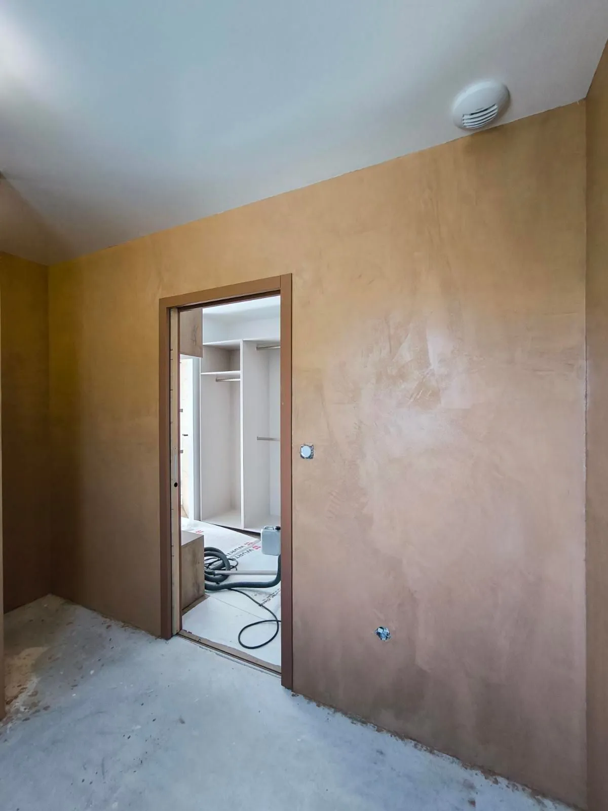 Mur de chambre en béton ciré ocre nuancé réalisé en Seine-Maritime