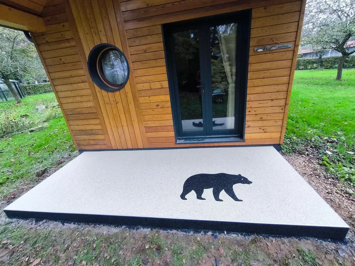 Terrasse de chalet en moquette de pierre claire avec motif ours incrusté