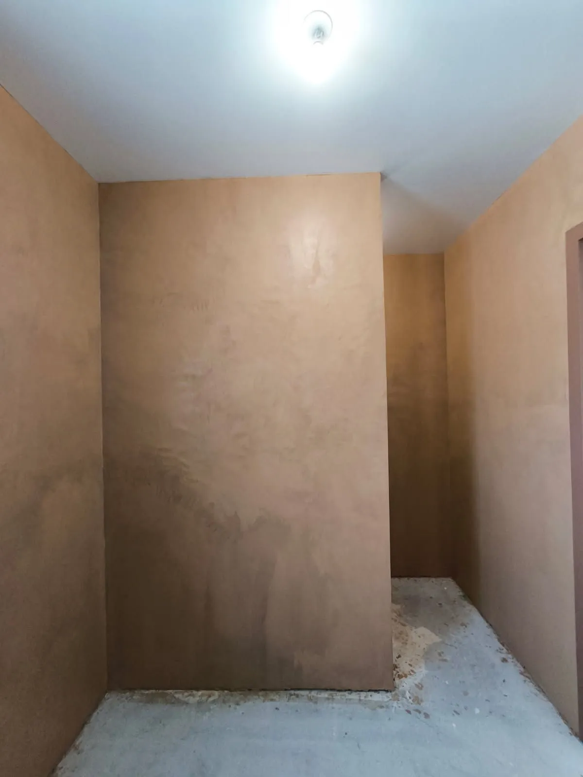 Mur en béton ciré teinte terre naturelle dans un couloir