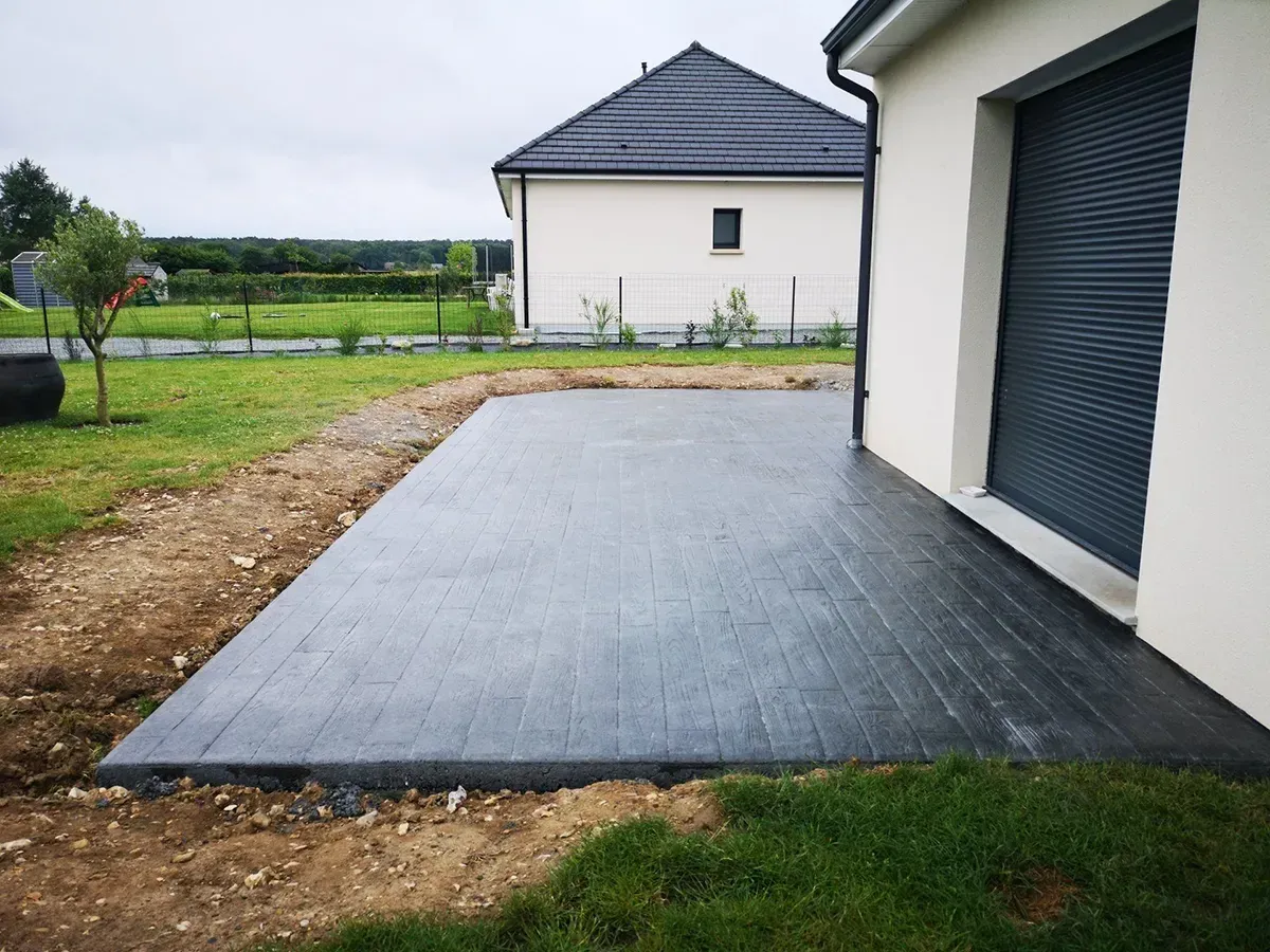 Allée d'entrée de garage en béton imprimé effet bois anthracite en Normandie
